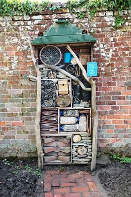 an insect hotel standing upright next to a garden wall