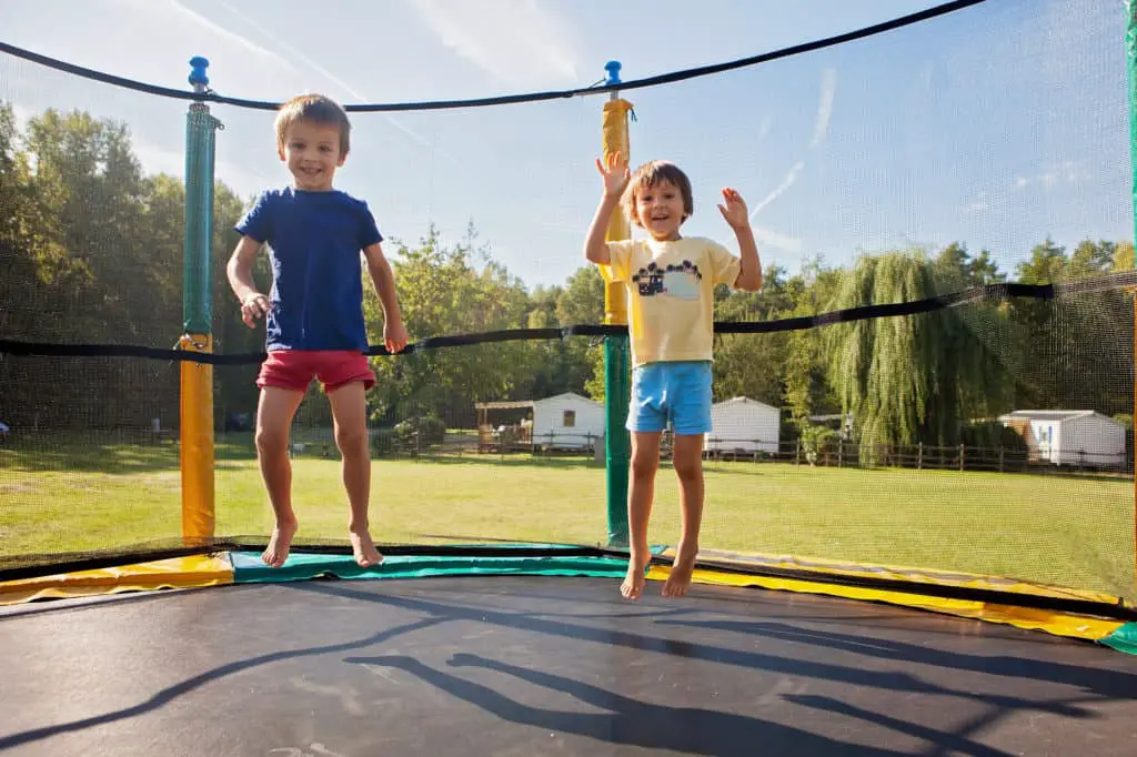 Two Kids Bouncing On A Trampoline
